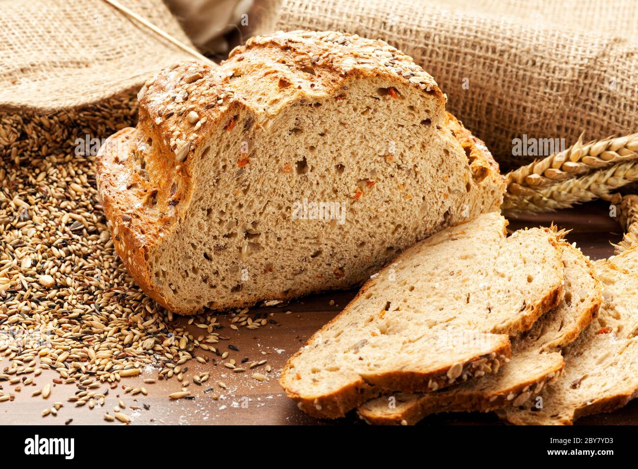 Vollkornbrot mit Scheiben, Sackleinen mit Korn im Hintergrund Stockfoto