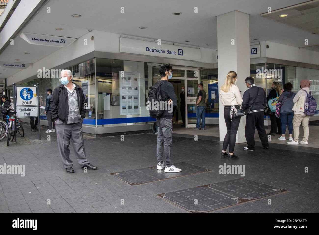 Vor der Deutschen Bank in Braunschweig bilden sich Menschen während der sozialen Distanzierungsmaßnahmen des Coronavirus nach Aufhebung der Sperre in Deutschland. Stockfoto