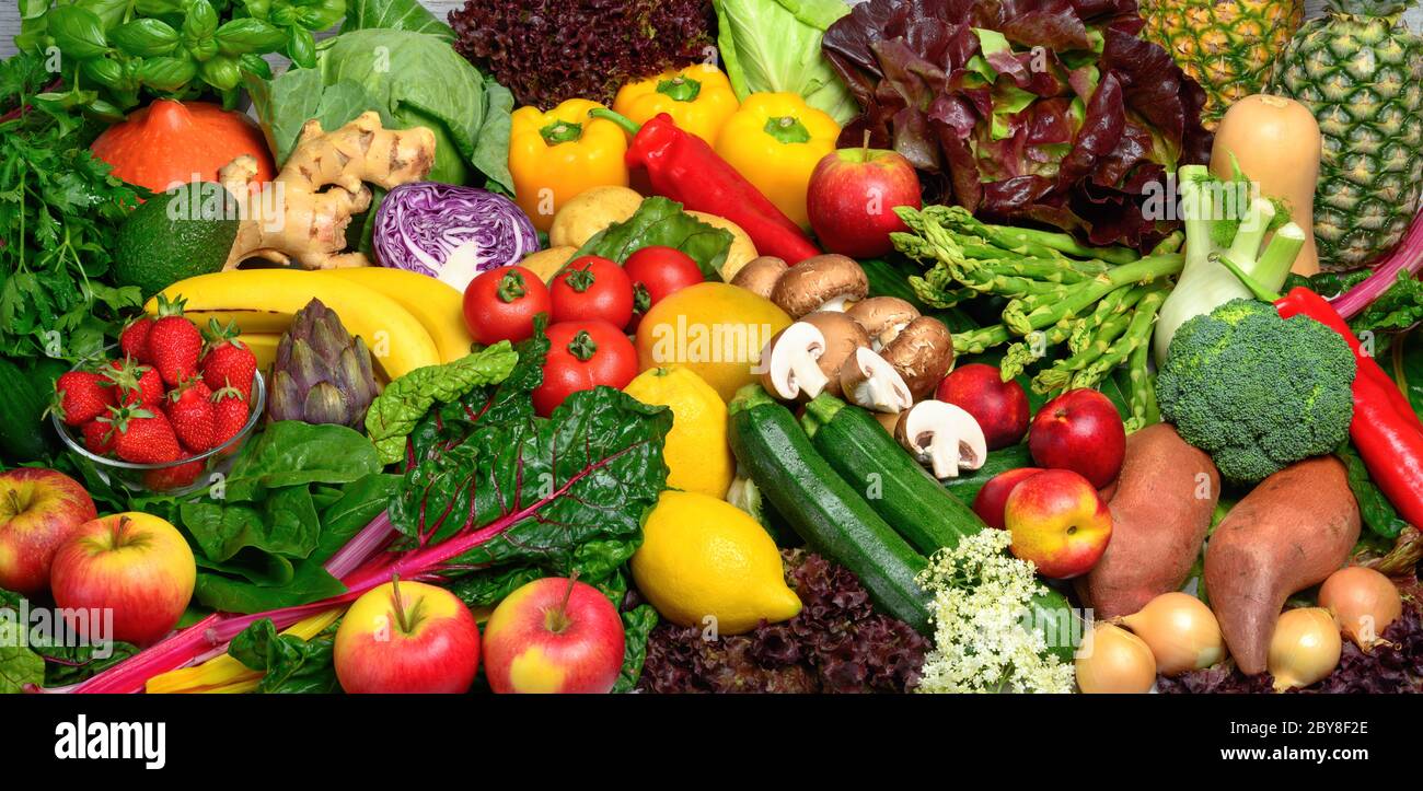 Ein Stapel Obst und Gemüse in vielen appetitlichen Farben angeordnet, lädt zu einem gesunden pflanzlichen Lebensstil und Selbstversorgung führen Stockfoto