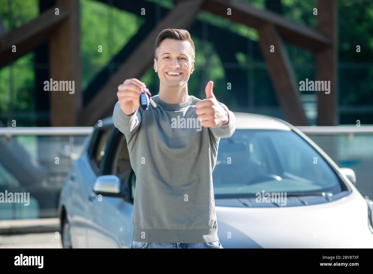 Zufriedener junger Mann mit Schlüssel, der alles zeigt, ist okay Stockfoto