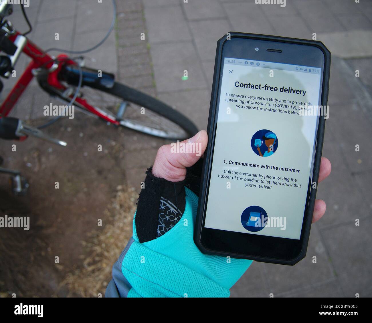 Deliveroo Cycle Kurier Food Delivery Rider überprüft kontaktlose Lieferführung auf Telefon-App. Stockfoto