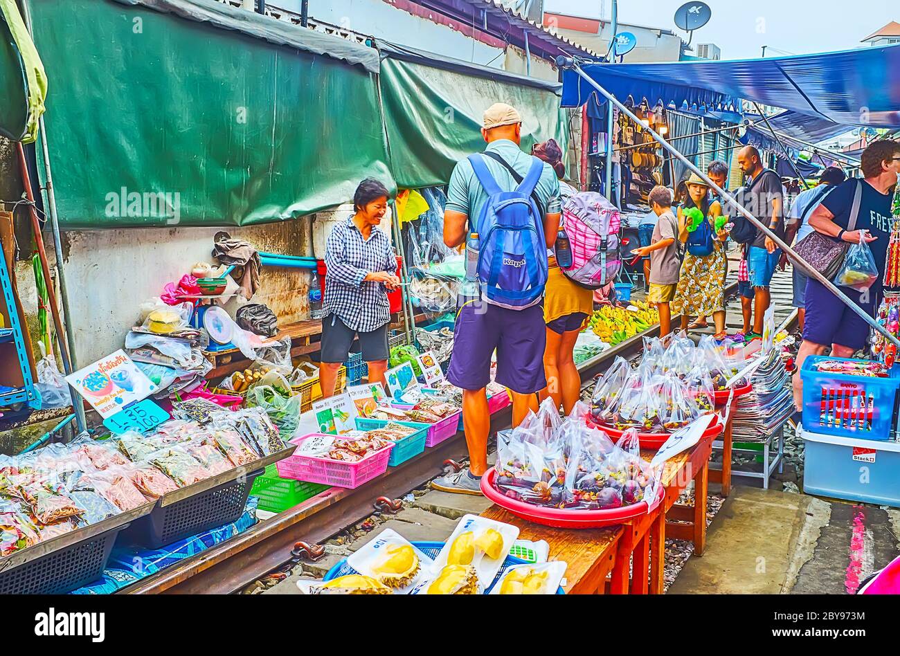 MAEKLONG, THAILAND - 13. MAI 2019: Die Touristen gehen die Eisenbahn und machen Shopping in Ständen des Maeklong Railway Market - der beliebte Touristenort in Stockfoto