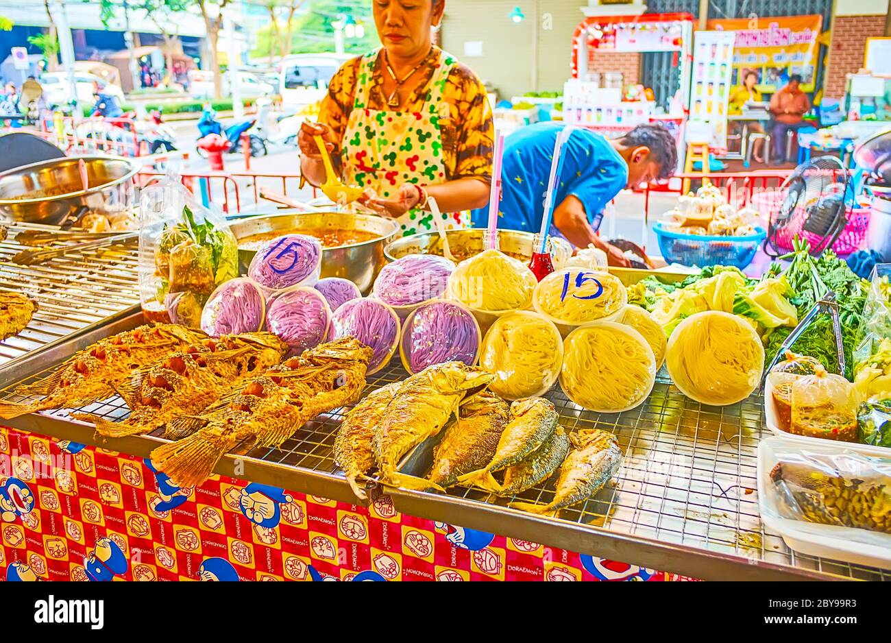 BANGKOK, THAILAND - 13. MAI 2019: Der Marktstand bietet gegrillten und frittierten Fisch mit Gemüse und farbigen Nudeln, Talad Saphan Phut Markt, auf Stockfoto