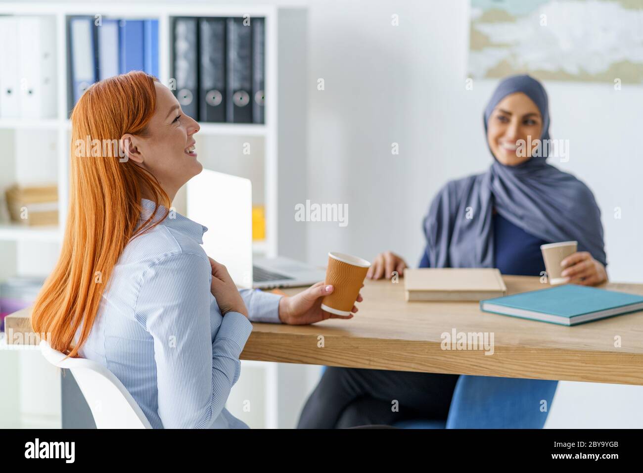 Frauen erzählen lustige Geschichten und trinken Kaffee während einer Pause Stockfoto