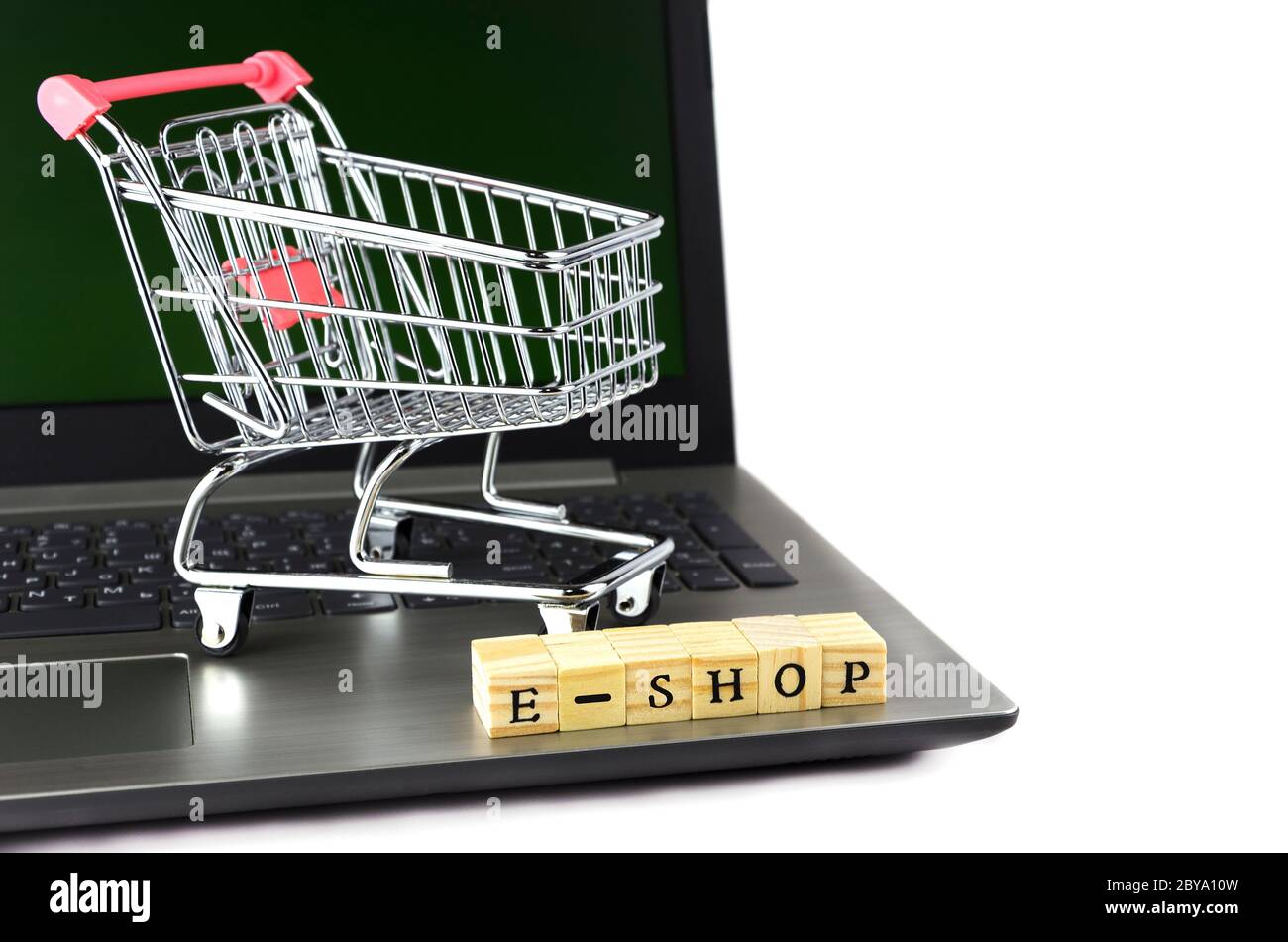 E - Shop gefaltet mit Würfeln mit Buchstaben auf dem Hintergrund eines Laptops und Trolley 2 Stockfoto