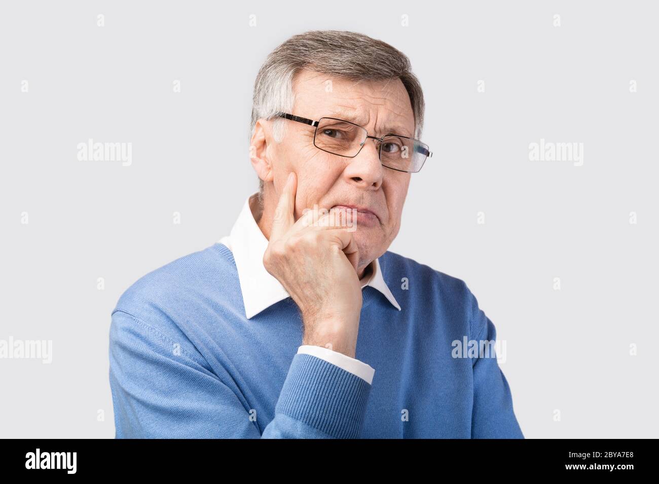 Nachdenklicher Senior Gentleman Denken Blick Auf Kamera Posing, Grauer Hintergrund Stockfoto