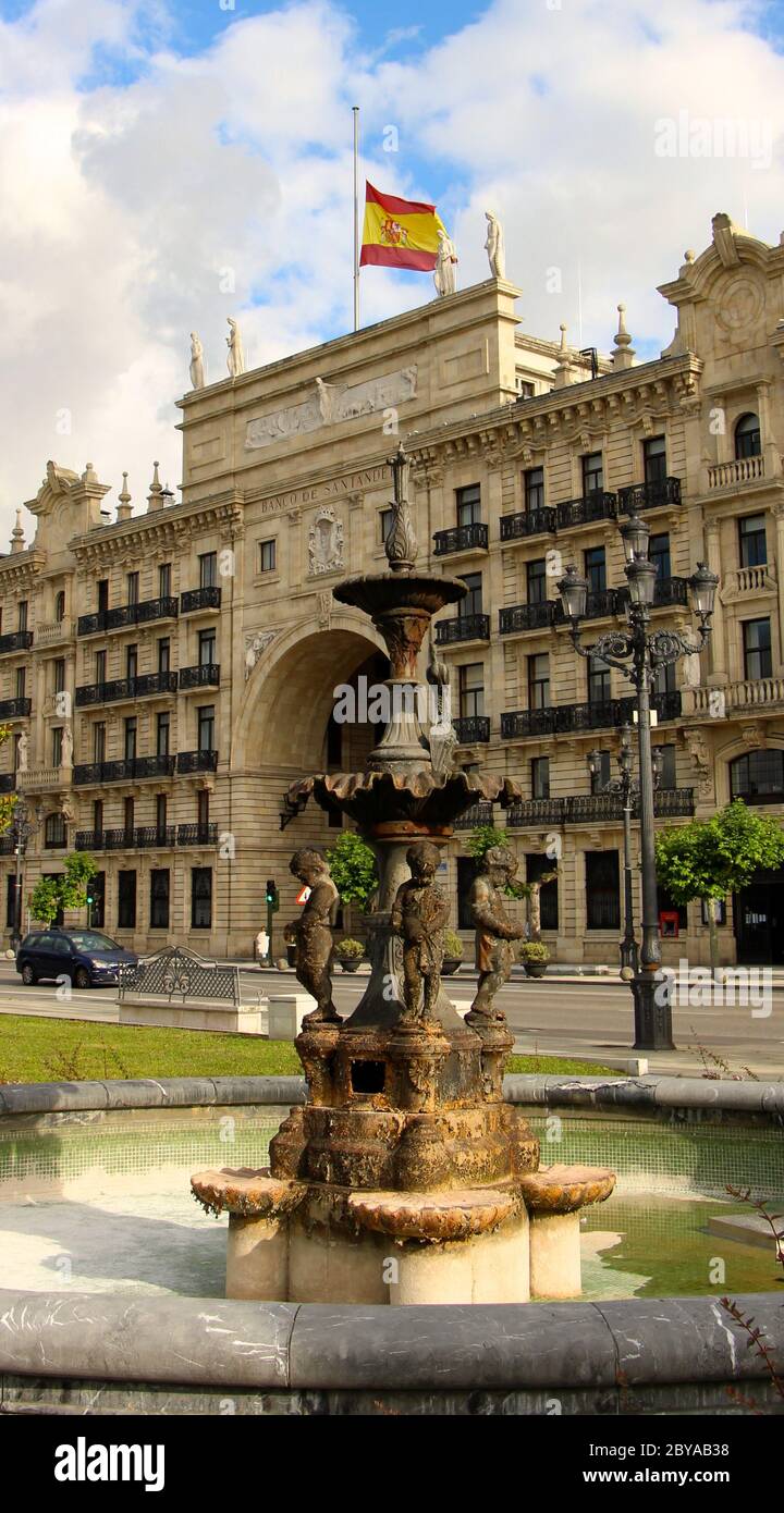 Ursprüngliches Hauptquartier der Bank Santander (Banco de Santander) spanische Nationalflagge am Halbmast und ein rostiger Brunnen aus den Gärten von Pereda Stockfoto