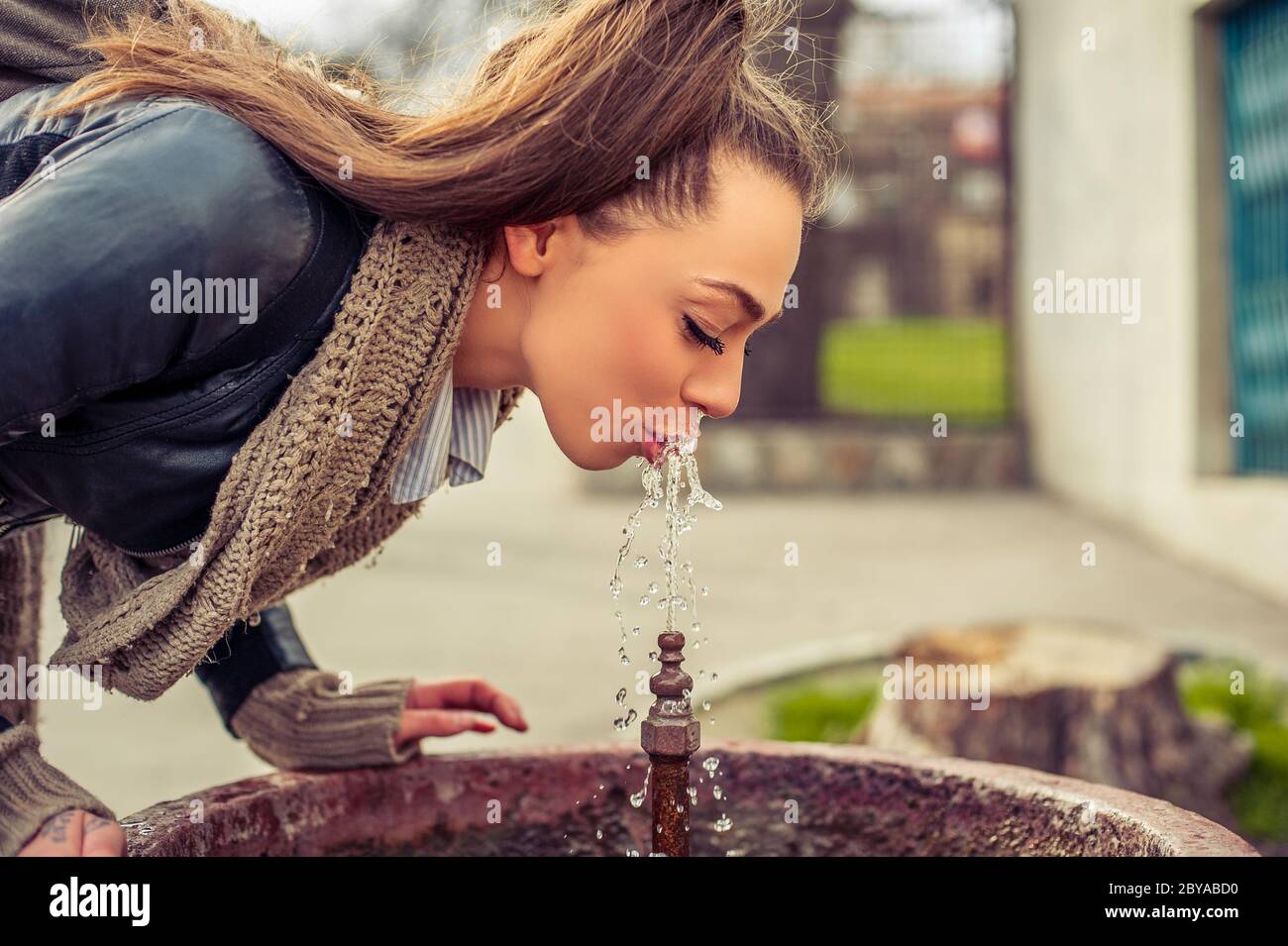 Junge Frau, die aus einem Brunnen trinkt Stockfoto