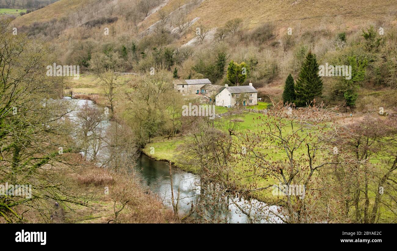 Blick hinunter ein Tal, ein kleines Bauernhaus und Nebengebäude neben einem kleinen Bach Stockfoto