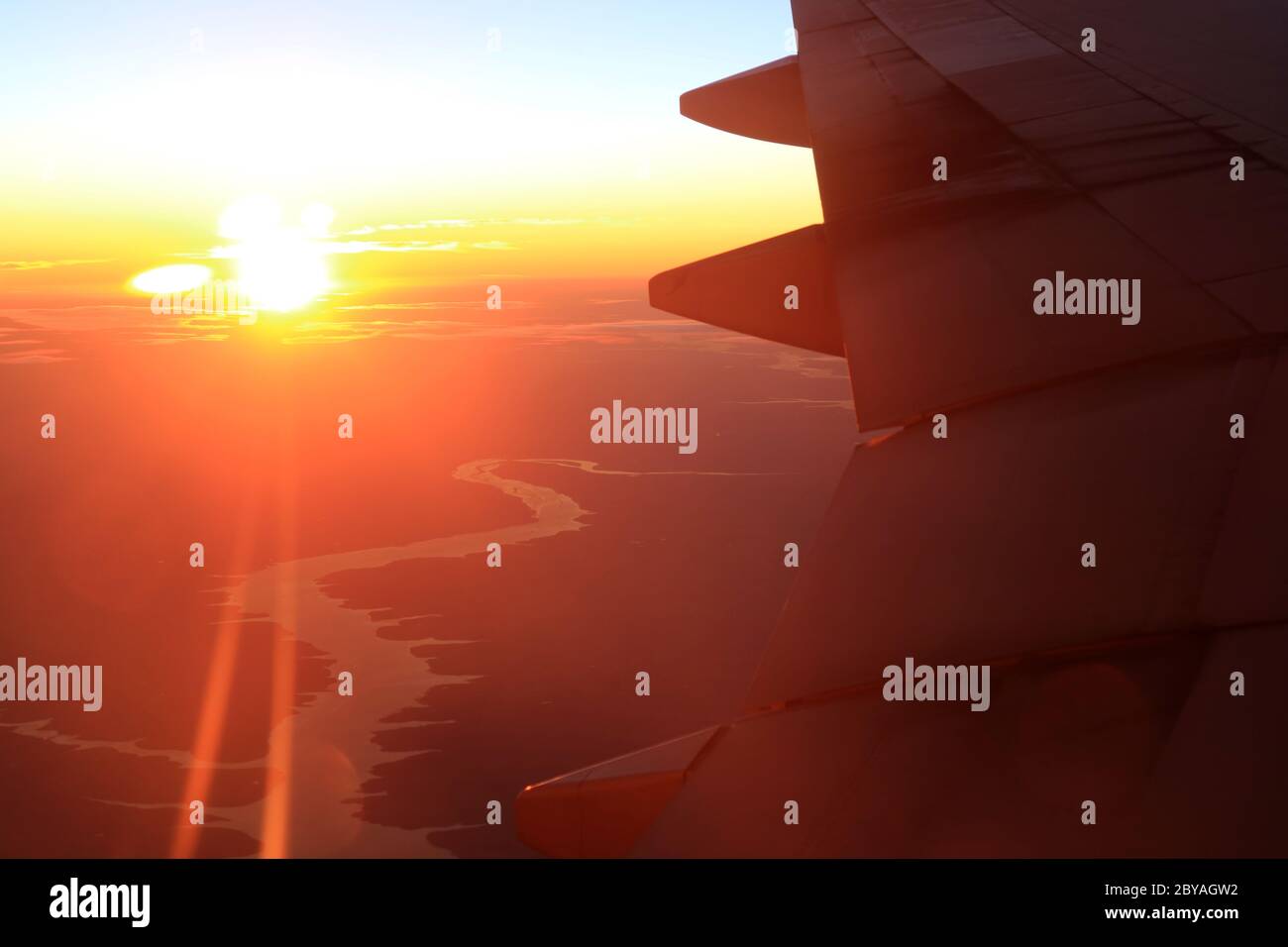 Fantastische Aussicht auf das Flugzeug fliegen im Sonnenlicht über ländliche Landschaft mit dem Fluss Stockfoto