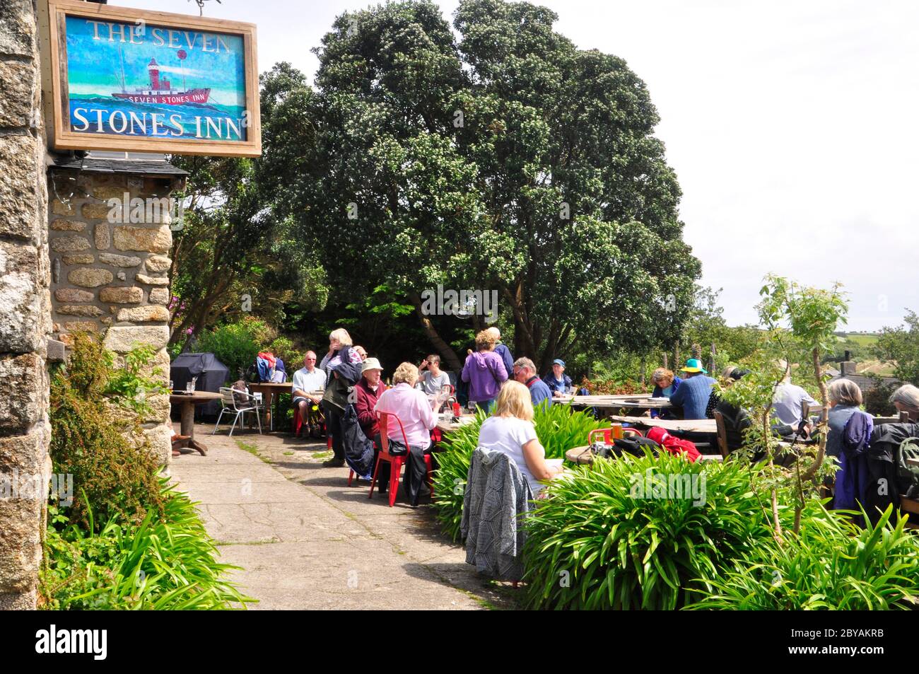 Touristen genießen die Aussicht und das Essen und die Sonne vor dem Seven Stones Inn auf St Martin's, einer der fünf bewohnten Inseln in den Inseln von SC Stockfoto