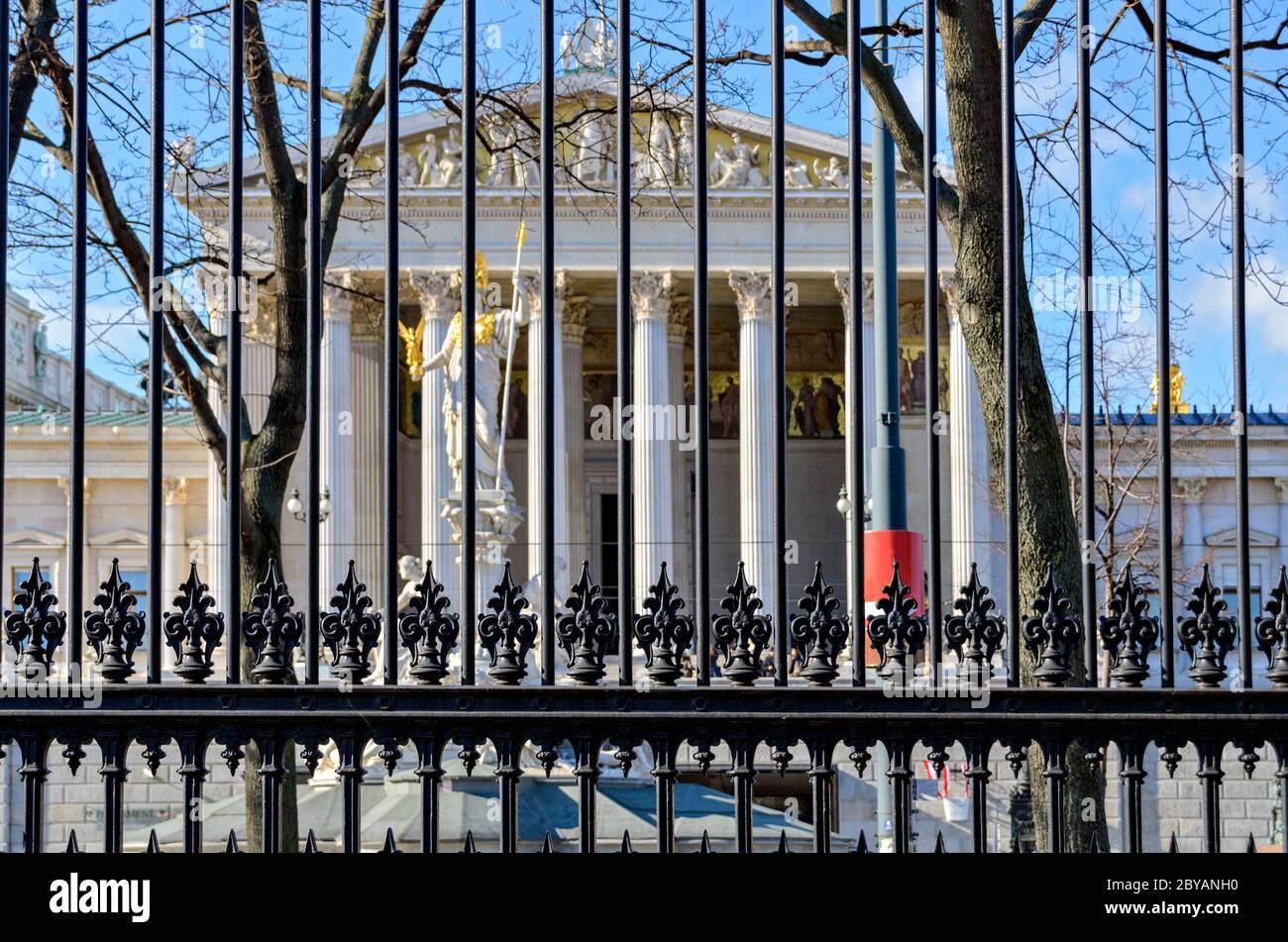 Blick durch einen historischen gusseisernen Zaun des Volksgartens auf das parlamentsgebäude in Wien, Österreich Stockfoto