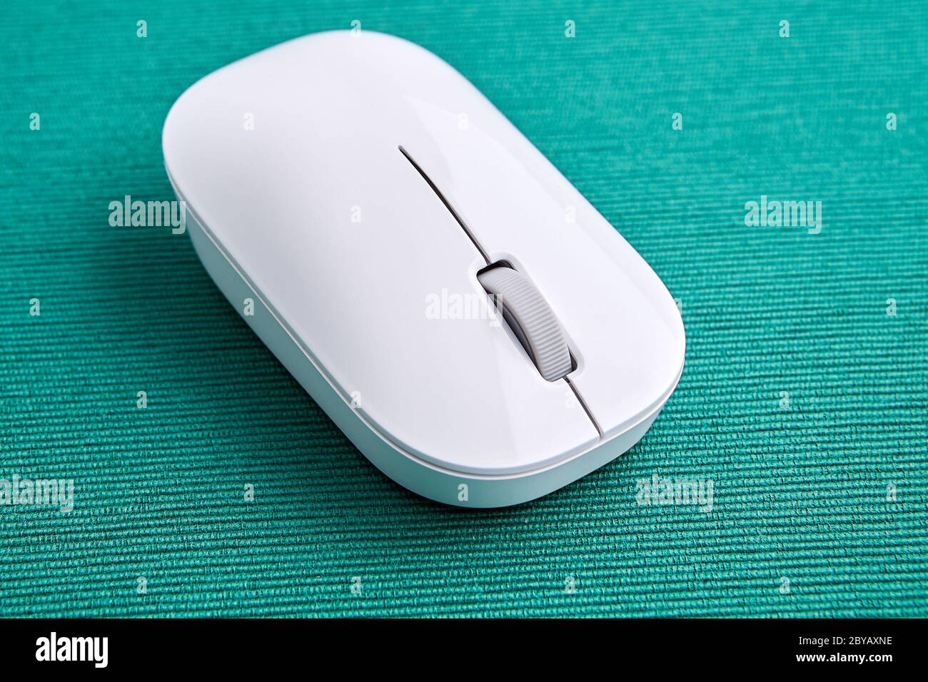 Drahtlose Computermaus aus weißem Kunststoff auf grünem Hintergrund, Nahaufnahme. Stockfoto