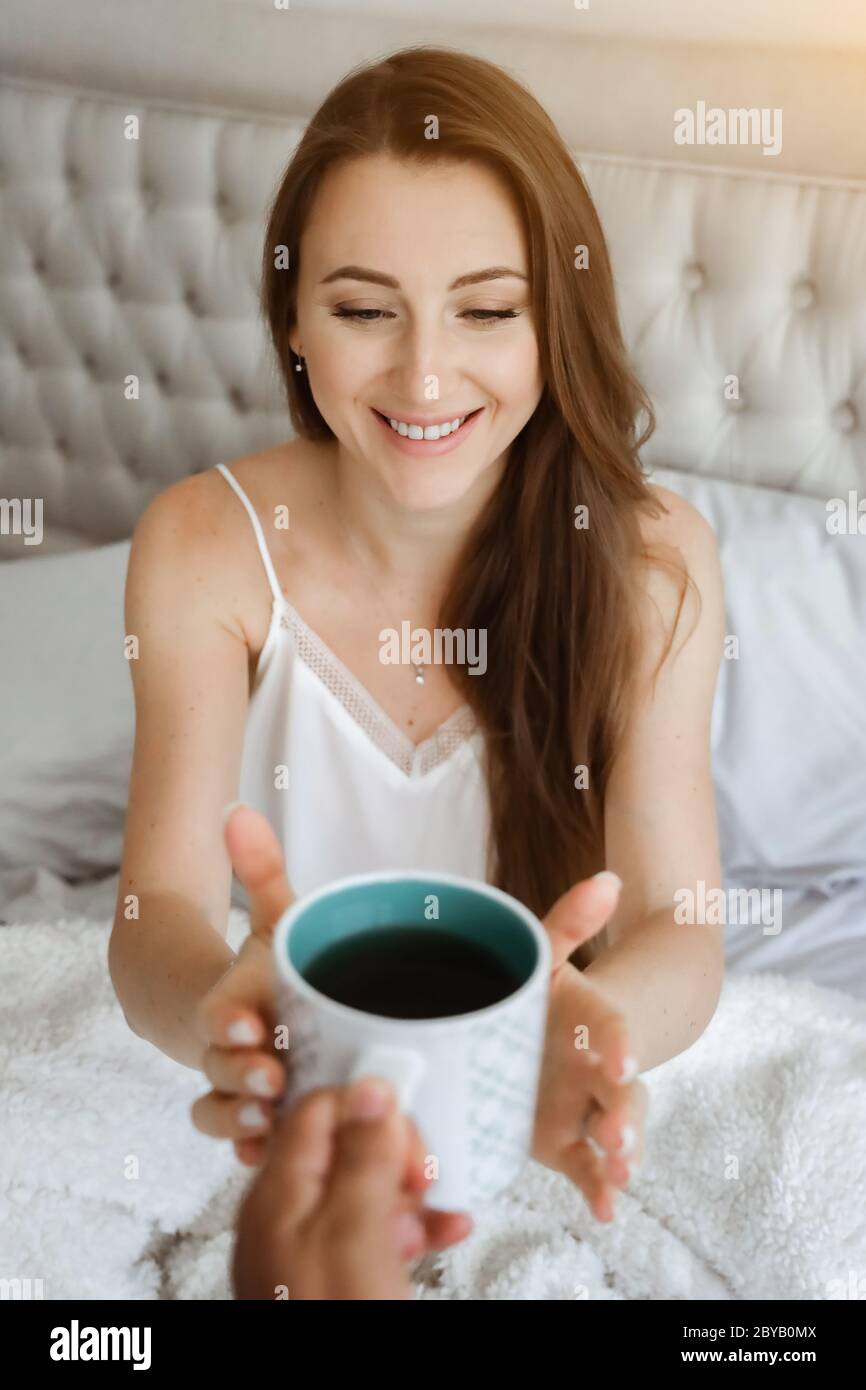 Frau im Bett trinkt Kaffee. Glückliches Mädchen. Morgenkonzept. Frühstück im Bett Stockfoto