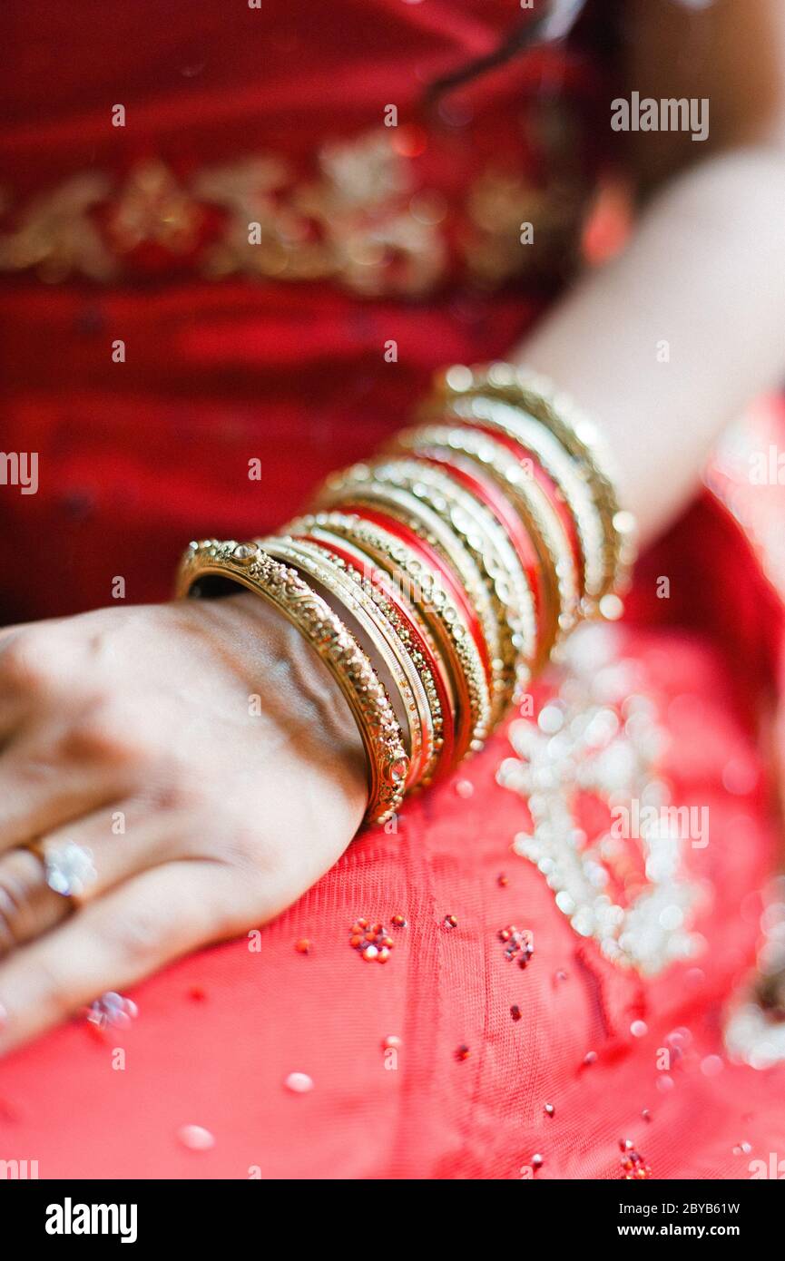Indische Braut mit Arm voller roter und goldener Armreifen Stockfoto