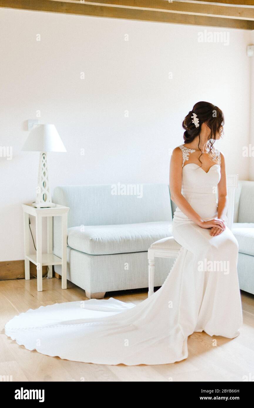 Braut sitzt auf Stuhl und schaut aus dem Fenster Stockfoto