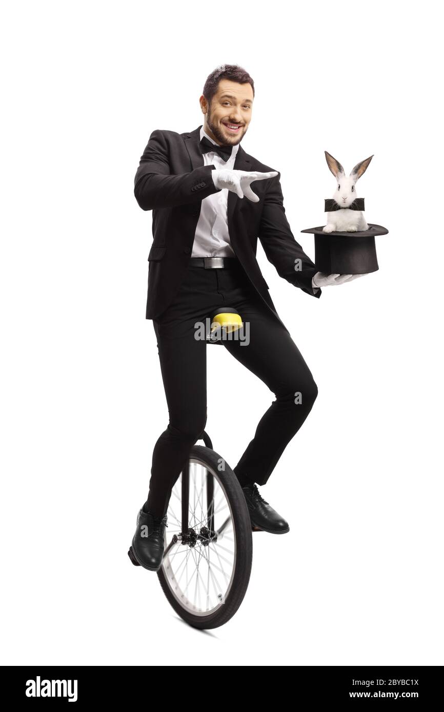 Magier auf einem Einrad und Durchführung eines Zaubertricks mit einem Hut und einem Kaninchen auf weißem Hintergrund isoliert Stockfoto