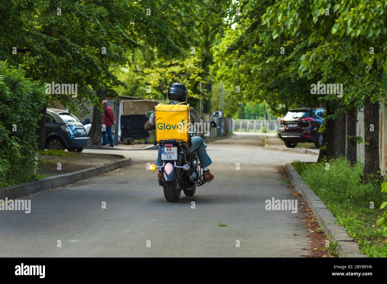 Kiew, Ukraine - 8. April 2020: Glovo Kurier mit einem gelben Rucksack, Lieferung auf einem Motorrad. Kurierdienste sind besonders relevant in großen Städten in Quarantäne. Stockfoto
