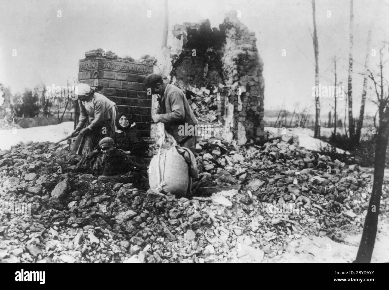 Zerstörtes polnisches Haus, das von den Russen bei ihrem Rückzug während des Ersten Weltkriegs 1915 verbrannt wurde. 4 Leute graben in den Trümmern eines Gebäudes. Stockfoto