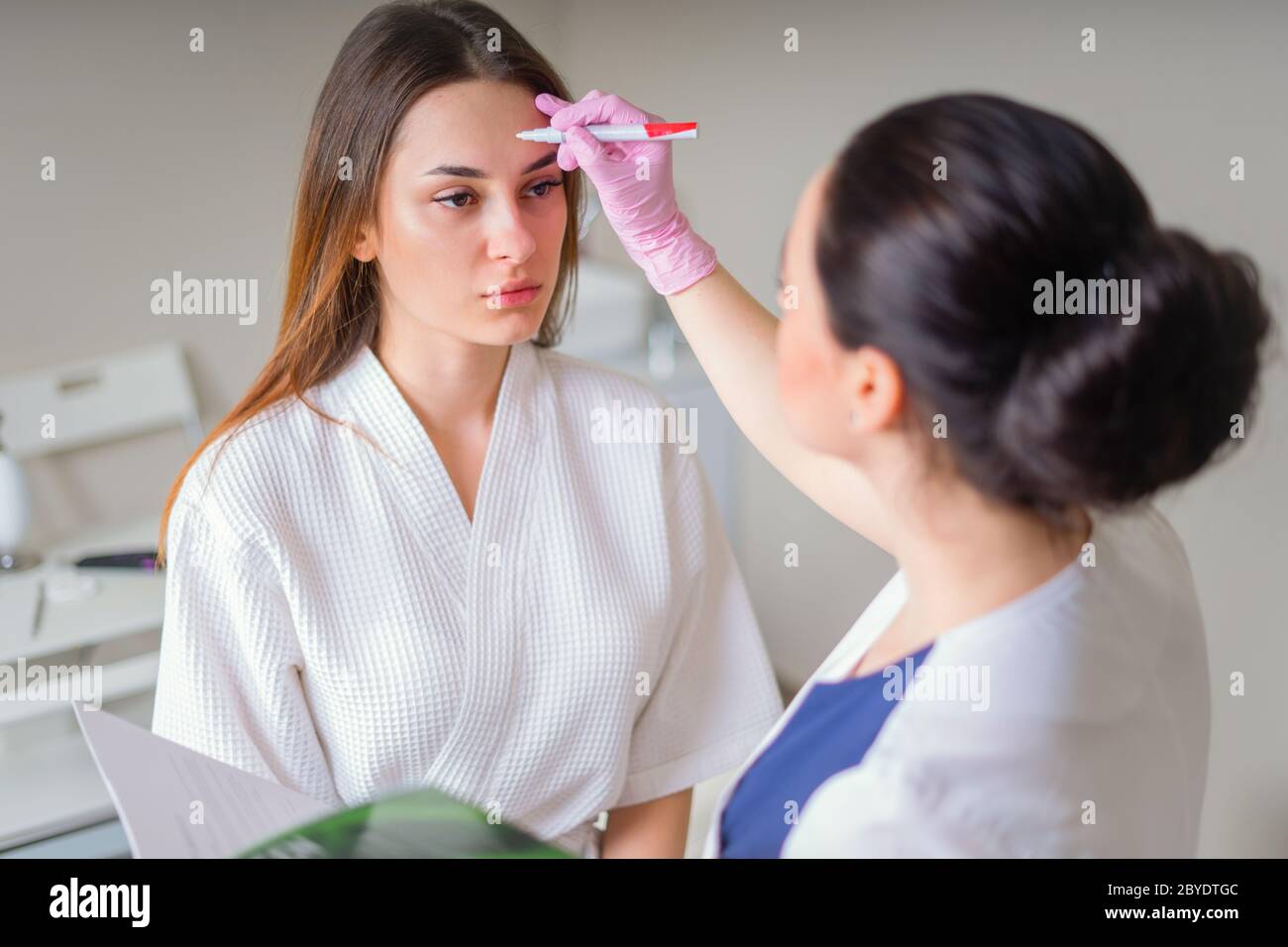 Kosmetologe bereit, Linien mit Marker auf dem Gesicht des Patienten zu malen Stockfoto