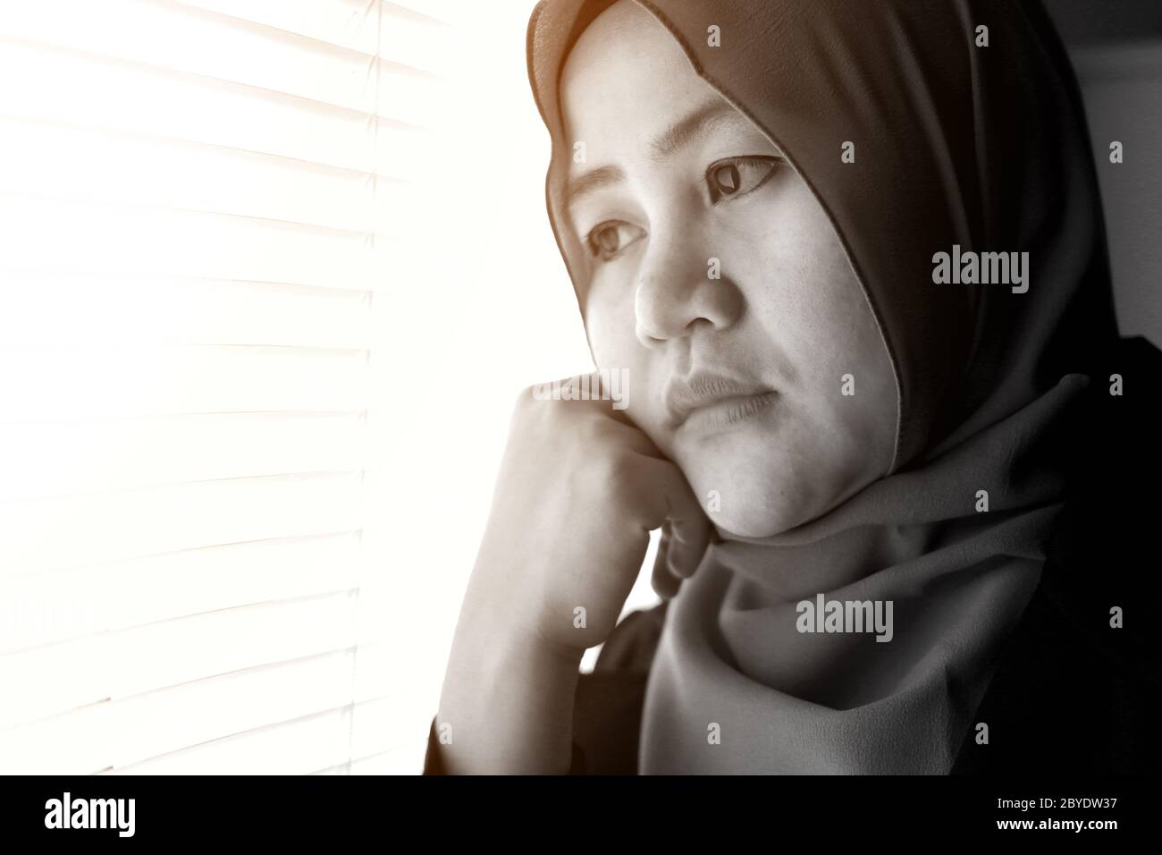 Nahaufnahme Porträt der traurigen asiatischen muslimischen Frau aus dem Fenster, einsame Traurigkeit Konzept Stockfoto