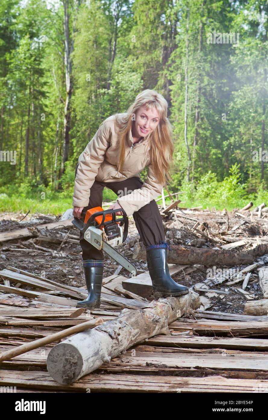 Die junge Frau in Holz Sägen einen Baum eine Kettensäge Stockfoto