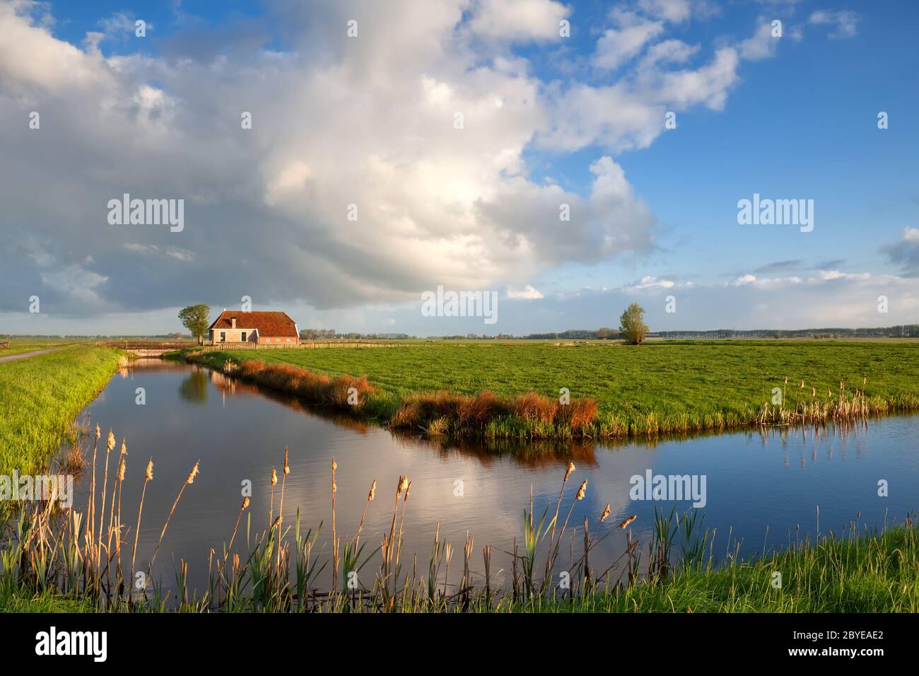 Kleines Haus, Fluss und weiße geschwollene Wolken Stockfoto