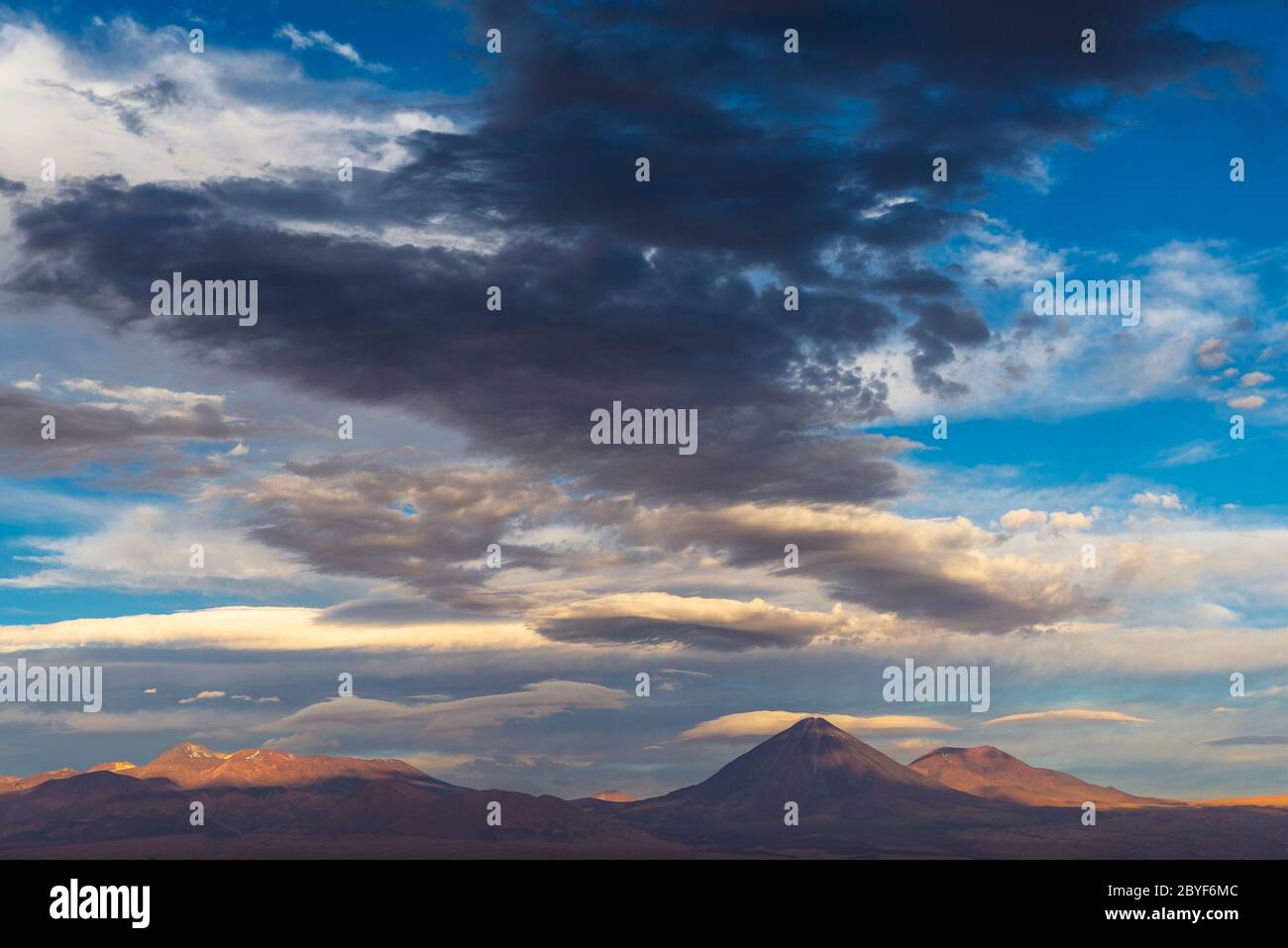 Regen und dunkle Wolken bei Sonnenuntergang über der Atacama Wüste mit dem Vulkan Licancabur, San Pedro de Atacama, Chile. Stockfoto Regen und dunkle Wolken bei Sonnenuntergang über der Atacama Wüste mit dem Vulkan Licancabur, San Pedro de Atacama, Chile. Stockfoto