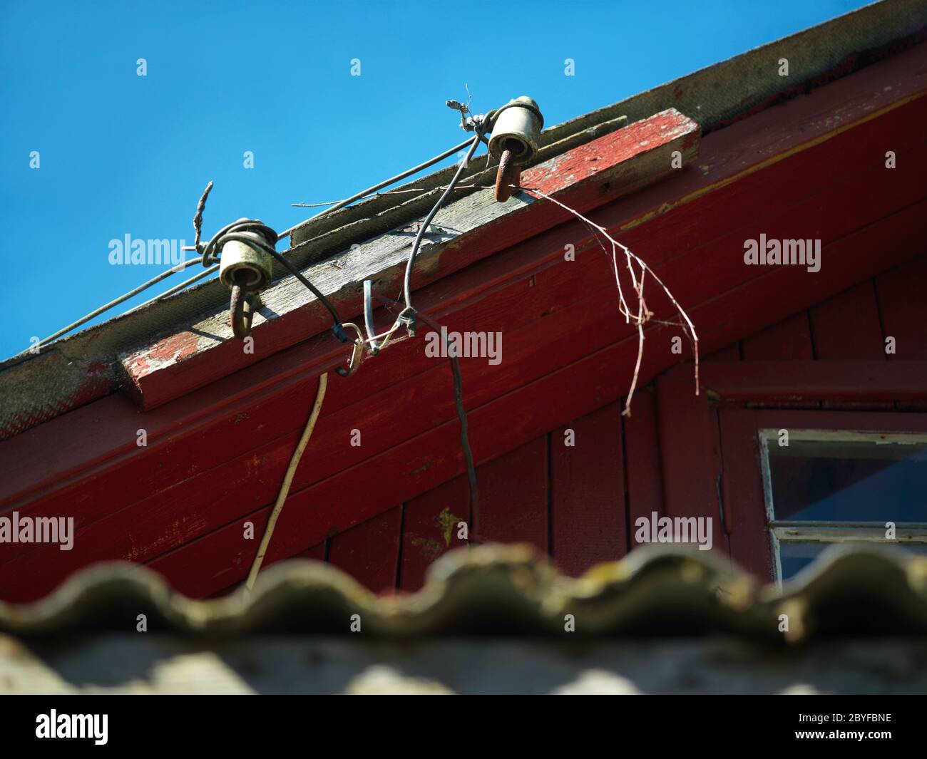 Kabelsalat und Porzellanisolatoren auf einem Dach gegen den Himmel Stockfoto