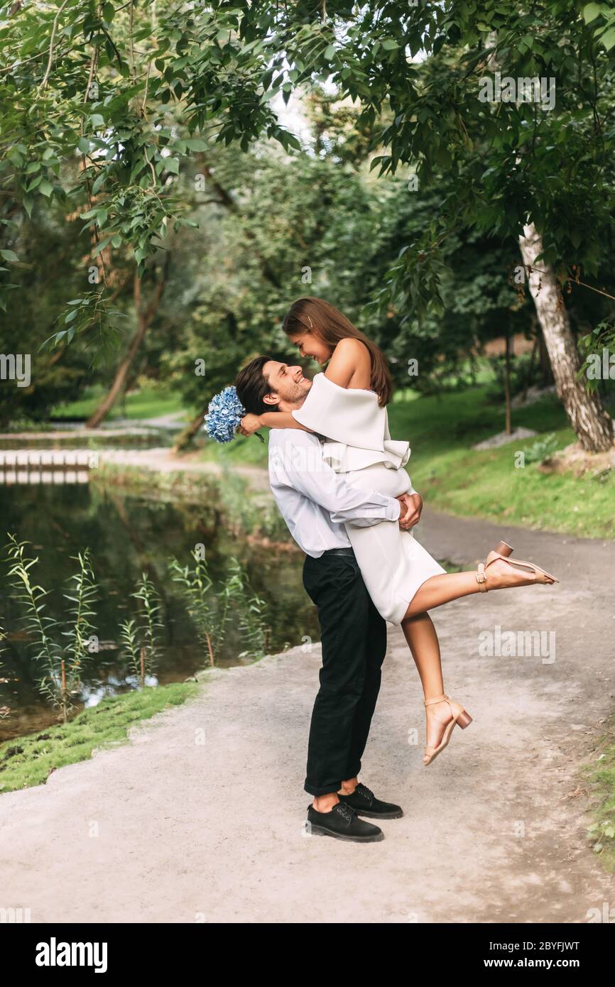 Bräutigam Heben Braut In Der Nähe Des Sees In Schönen Park, Vertikal Stockfoto
