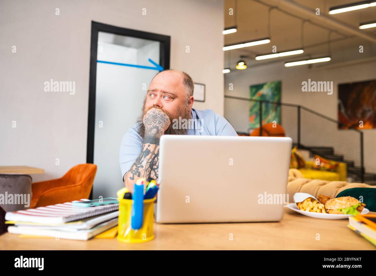 Kahl tätowierten Mann sitzt am Tisch und sieht nachdenklich Stockfoto