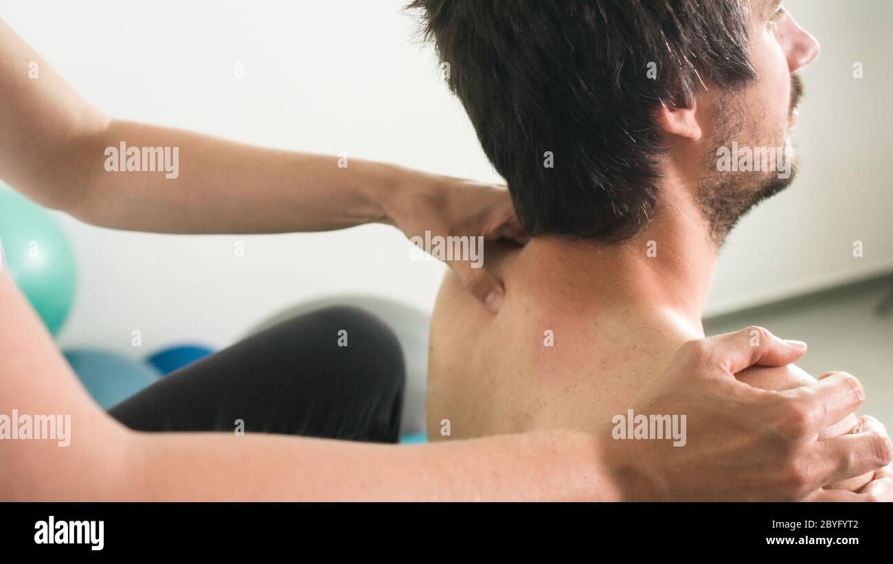 Physiotherapeut, der Massage und Dehnung mit Person auf einem Behandlungstisch macht. Stockfoto