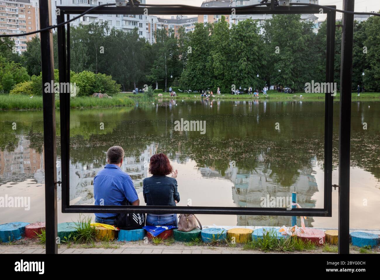 Moskau, Russland. 9. Juni 2020 die Menschen entspannen sich am Ufer des Teiches im Park des Dmitrowski Bezirkes der Stadt Moskau bei warmem Wetter im Sommer. Ab dem 9. Juni haben die Moskauer Behörden das Selbstisolationsregime, das digitale Passsystem für die Stadtbesichtigung und den Wanderplan aufgehoben; alle Moskauer Residenzinnen und Residenzinnen durften ohne Einschränkungen ausgehen und öffentliche Plätze besuchen Stockfoto