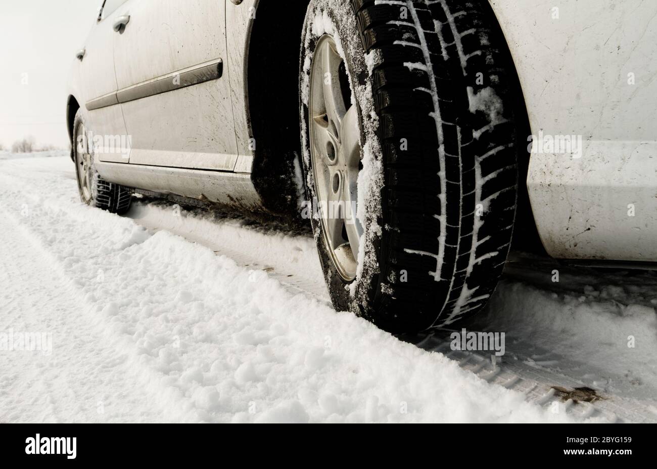 Nahaufnahme von einem Pkw-Reifen auf einer verschneiten Straße Stockfoto