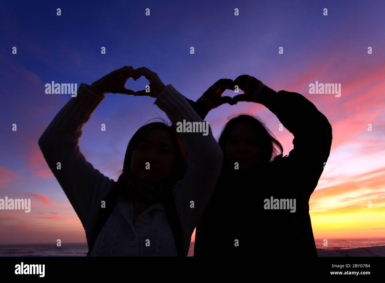 Silhouette der beiden Mädels bilden ihre Hand zur Herzform Stockfoto