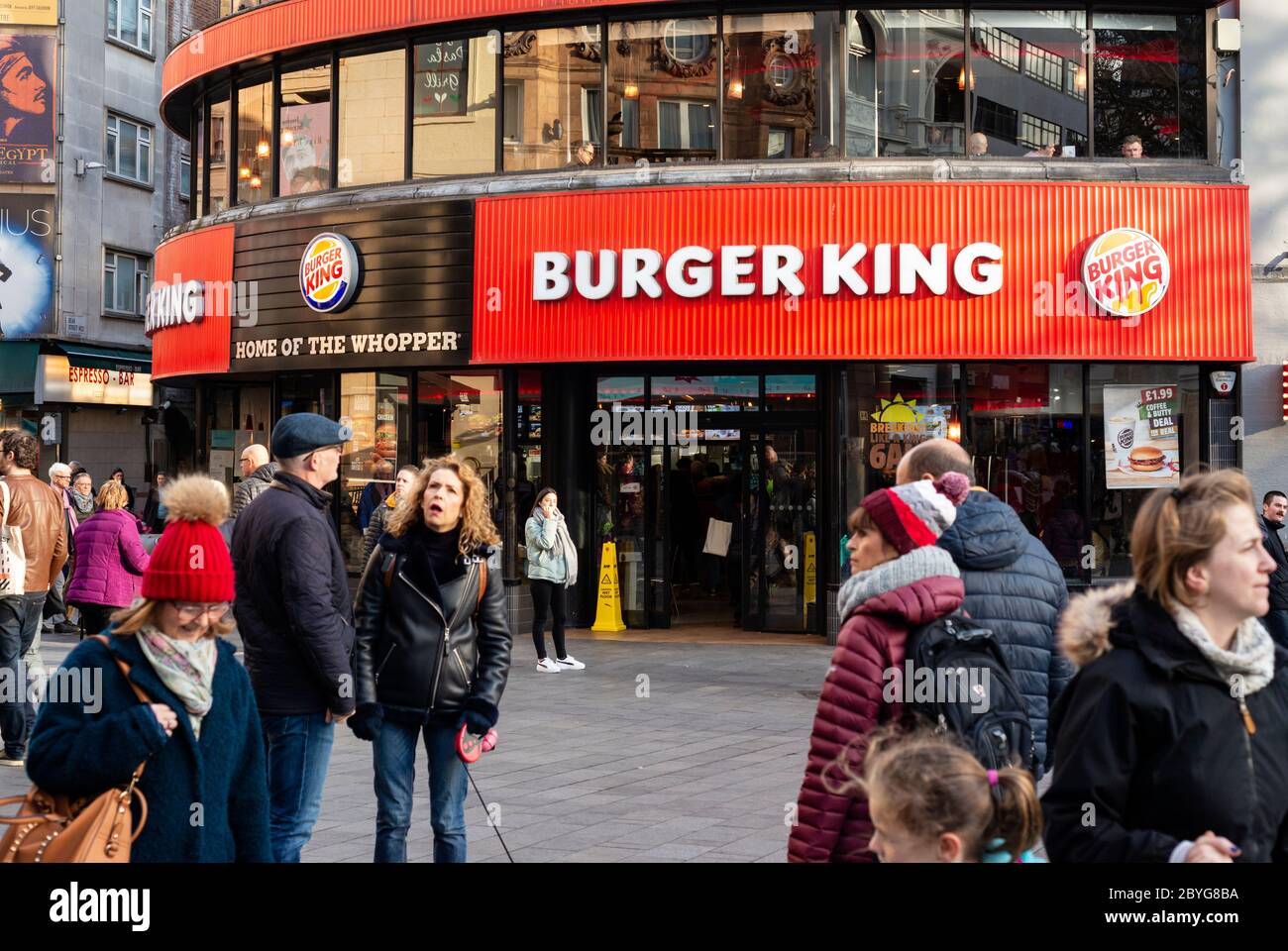 Geschäftige Stadtsicht auf Menschen und Touristen vor dem Burger King Fast Food Outlet Restaurant mit roter Fassade im Leicester Square West End London, Großbritannien Stockfoto