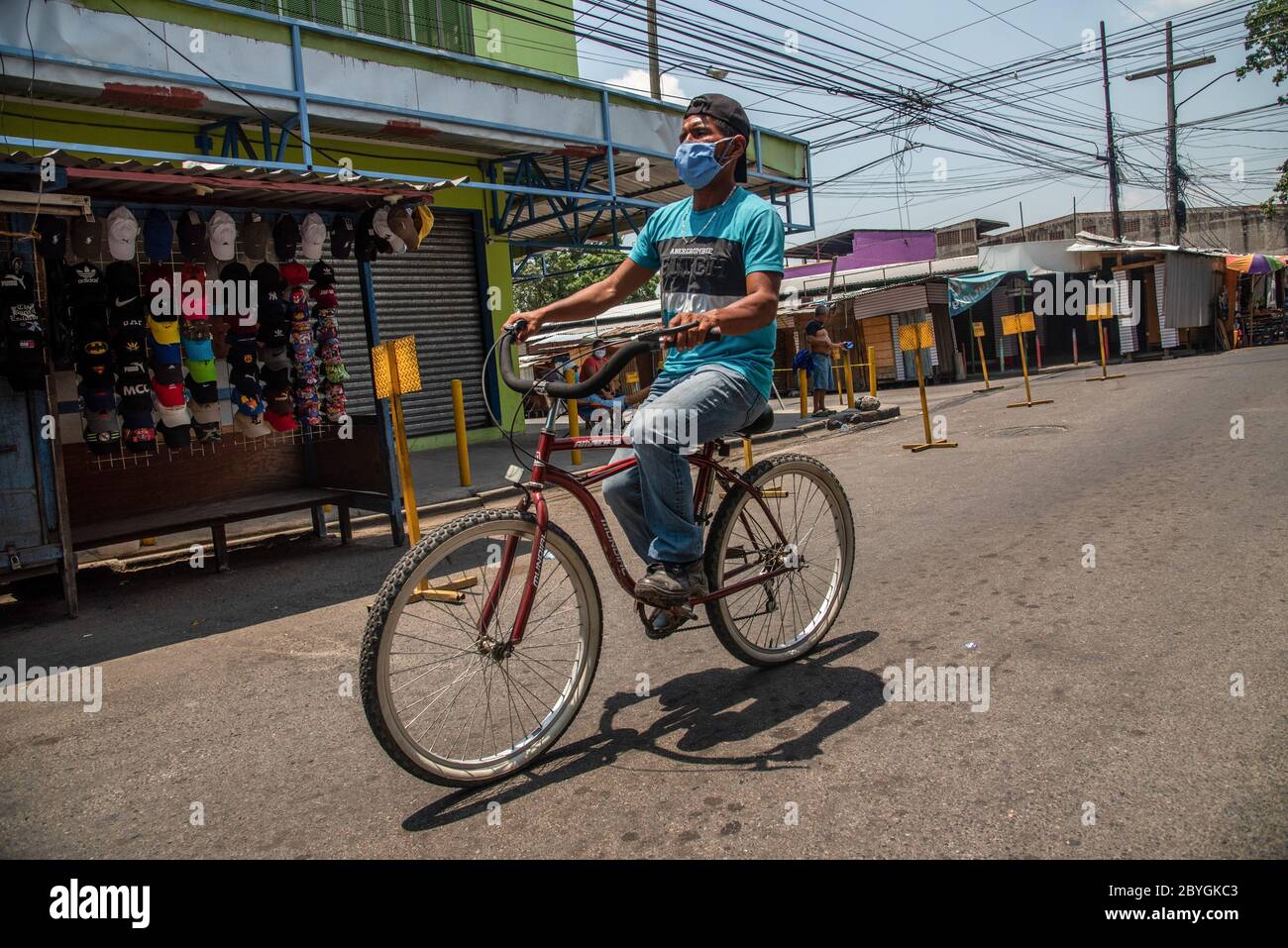 San Pedro Sula, Honduras. Mai 2020. Ein Mann, der vorbeugend eine Gesichtsmaske trägt, fährt mit dem Fahrrad durch einen verlassenen Marktplatz. Honduras hat eine "intelligente Wiedereröffnung" ins Land gebracht, die es allen kommerziellen Unternehmen ermöglichte, sich zu öffnen, aber alle Angestellten und Kunden dazu aufforderte, Masken zu tragen. Quelle: SOPA Images Limited/Alamy Live News Stockfoto