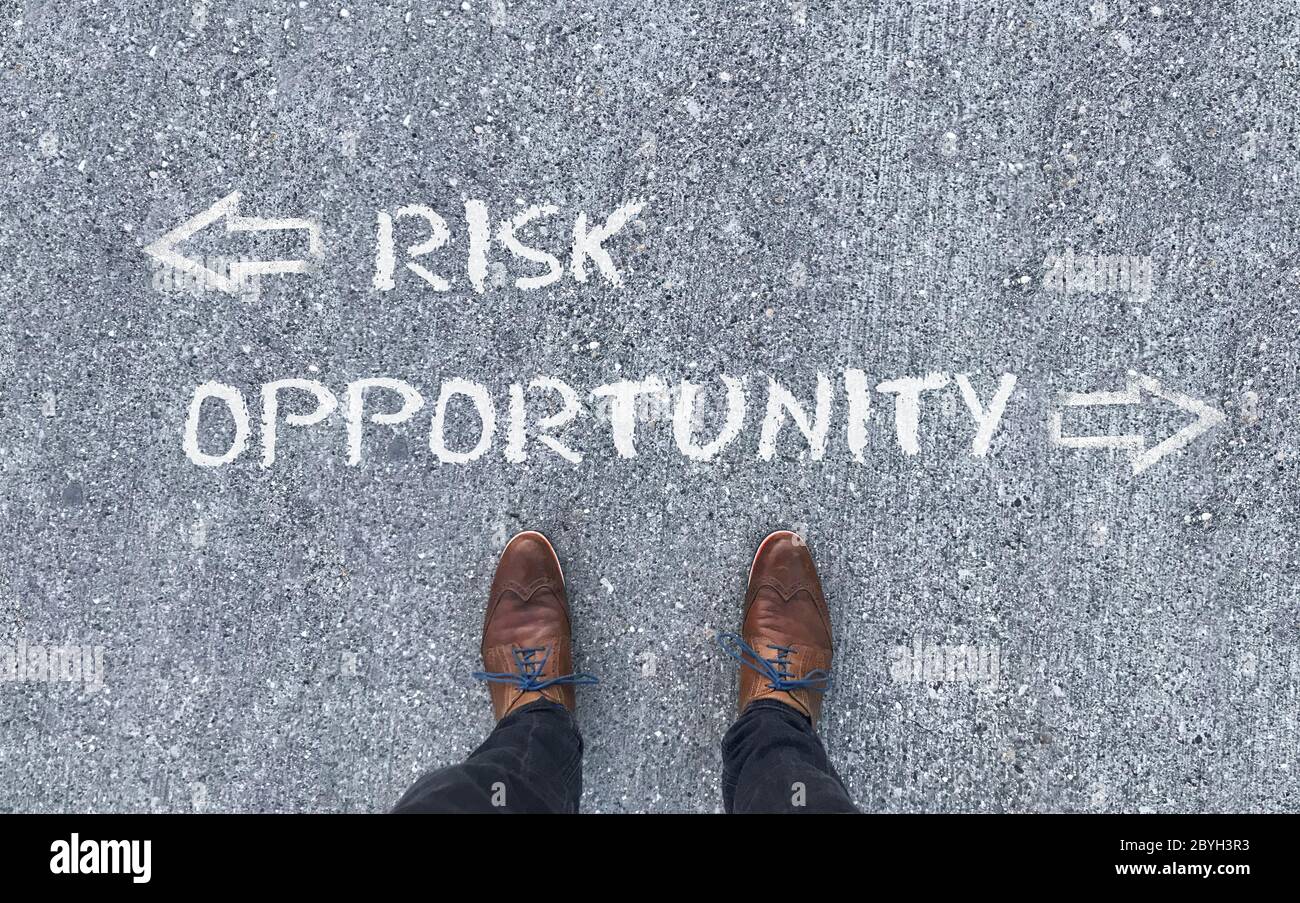 Draufsicht auf einen Mann, der vor den Worten „Risiko“ und „Gelegenheit“ steht, mit Pfeilen, die nach links und rechts zeigen Stockfoto