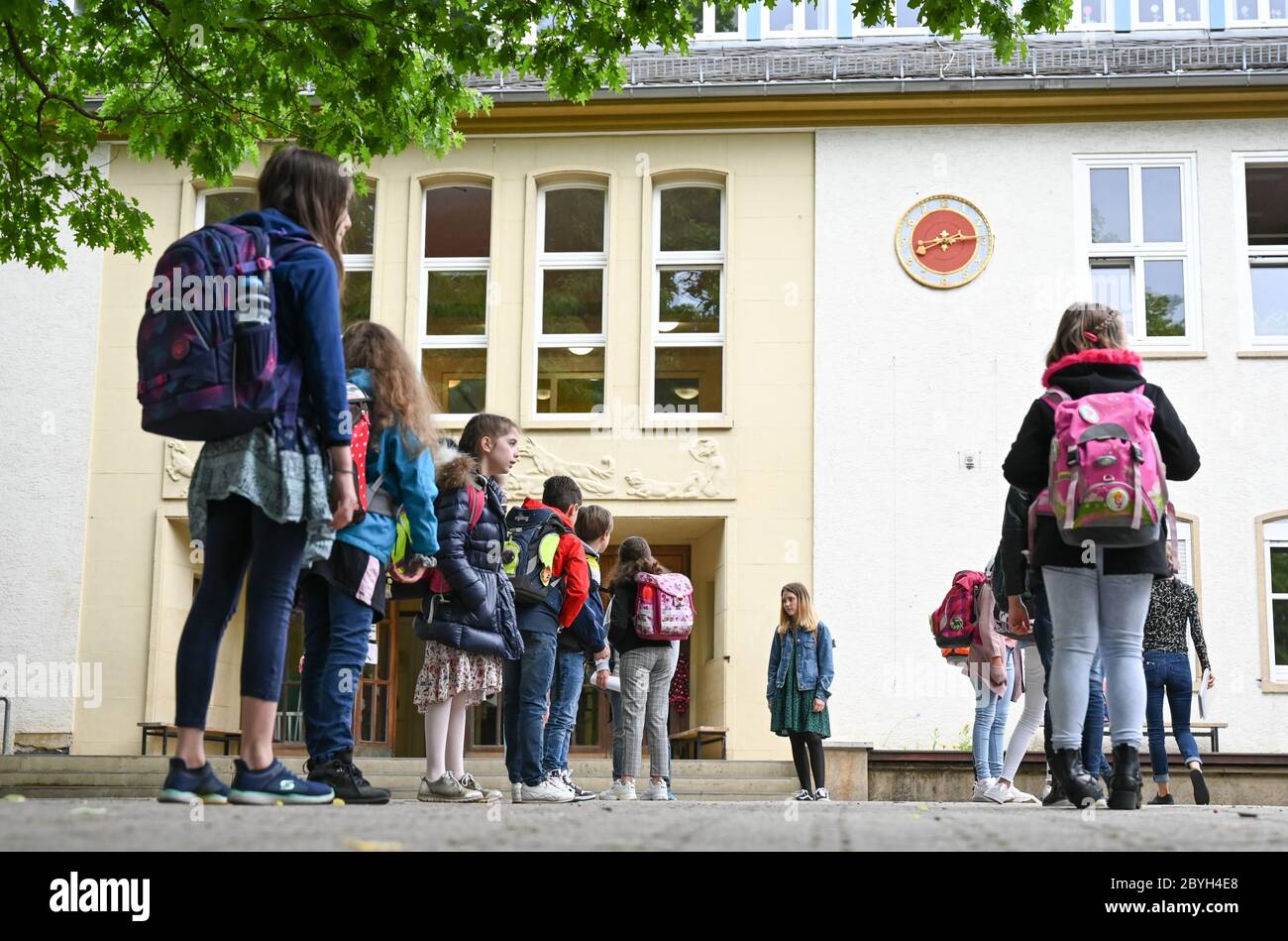 10. Juni 2020, Hessen, Wiesbaden: Schülerinnen und Schüler der vierten Klasse der Robert Schumann Grundschule stehen auf dem Schulhof weit voneinander entfernt vor dem Klassenzimmer. Am 22. Juni starten die Hessischen Grundschulen wieder mit gemeinsamen Präsenzkursen für alle Kinder. Die Distanzregel gilt dann nicht mehr. Foto: Arne Dedert/dpa Stockfoto