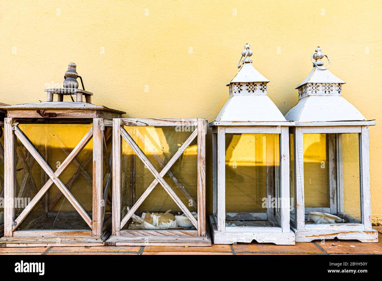 Italien. Vier hölzerne Gartenlaternen, die unter einer gelben Wand platziert sind. Stockfoto