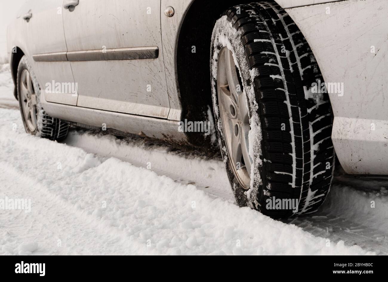 Nahaufnahme von Pkw-Reifen auf einer verschneiten Straße - Sepia-Farbton Stockfoto