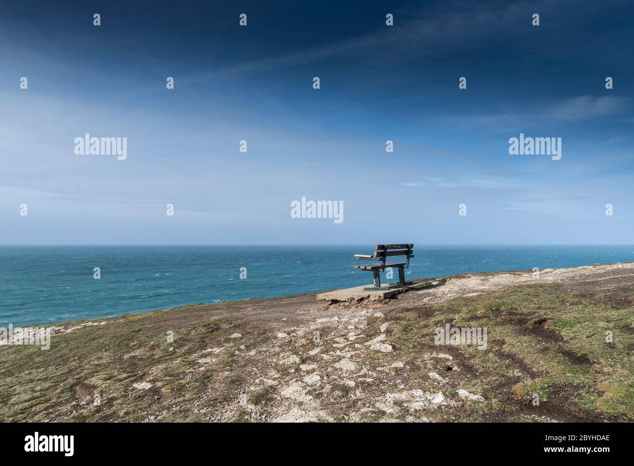 Eine Bank auf der Spitze eines runden, bronzezeitlichen Kairns auf dem gesamten Point East in Newquay in Cornwall. Stockfoto