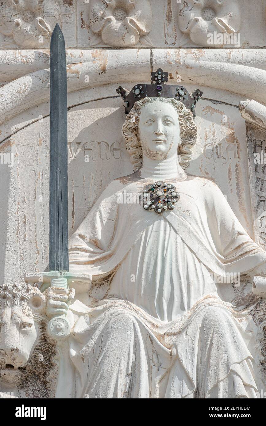 Alte Fassadenskulptur einer Prinzessin mit Schwert und Löwen als oberste Dekoration des Dogenpalastes in Venedig, Italien, Nahaufnahme, Details Stockfoto