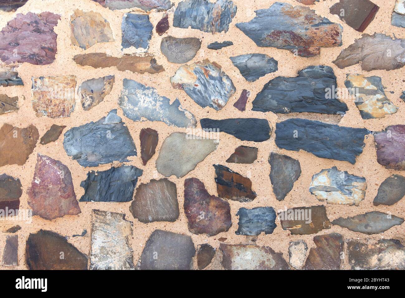 Steinmauer Hintergrund, Gebäudemerkmal. Textur von dicken und starken Wand von rauen Steinen in verschiedenen Formen und Größen Stockfoto