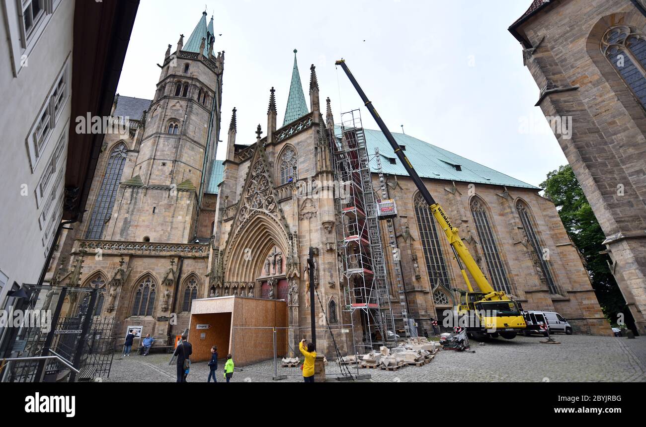 Erfurt, Deutschland. Juni 2020. Am dreieckigen Portal des Erfurter Doms werden die schweren Steinblöcke des restaurierten Wimperg mit einem Kran angehoben, um sie wieder am Portal der Jungfrau Maria anzubringen. Im Laufe der Jahrhunderte haben Zeit und Wetter am mächtigen Dreiecksportal geknabert. Quelle: Martin Schutt/dpa-Zentralbild/dpa/Alamy Live News Stockfoto