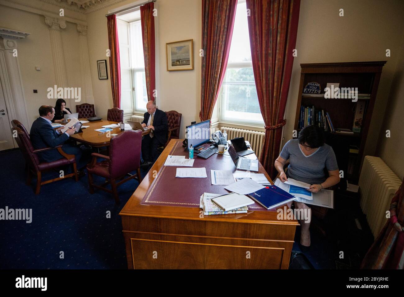 Hinter den Kulissen von Stormont während der Pandemie von 19 mit der ersten Ministerin Arlene Foster (rechts) in ihrem Büro mit ihrem Juniorminister Gordon Lyons (links) und den SPADs Emma Little-Pengelly (zweite links) und Dr. Phillip Weir (Mitte). Stockfoto