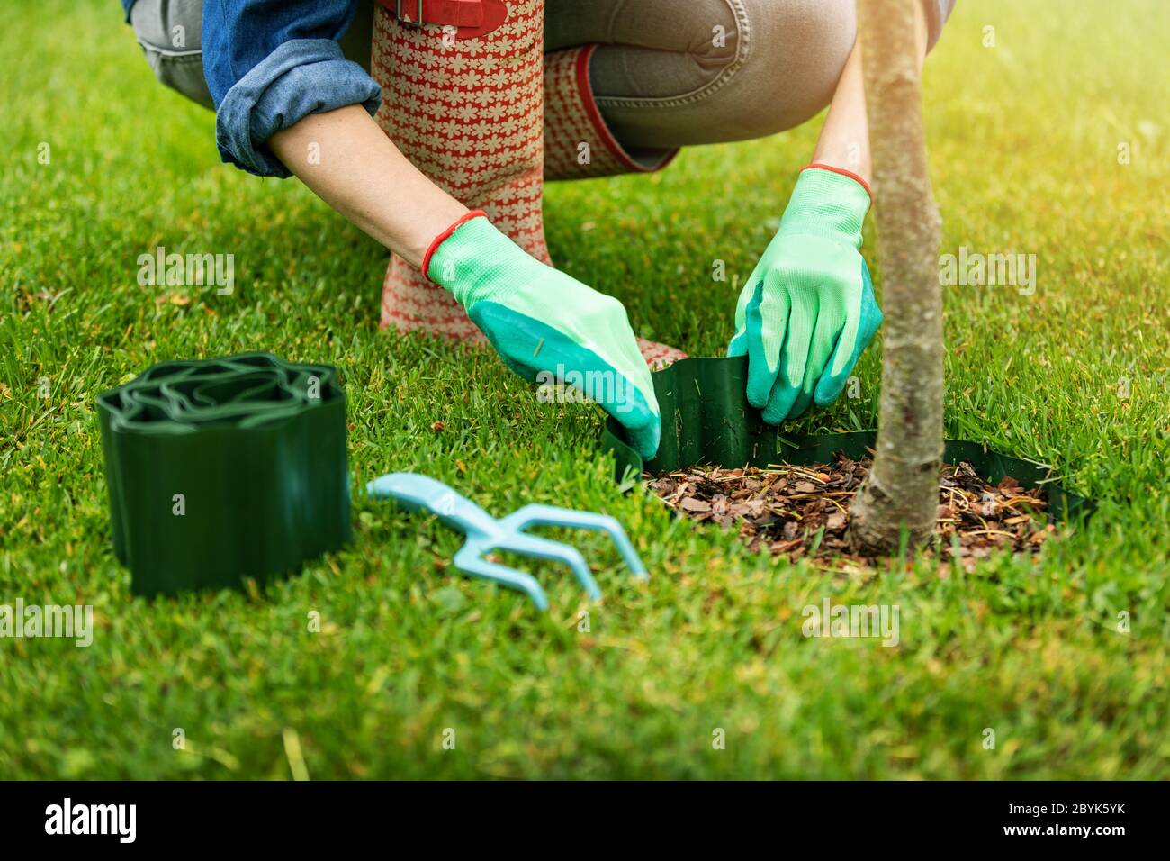 Gärtner installieren Kunststoff Gras Rand um den Baum im Garten Stockfoto