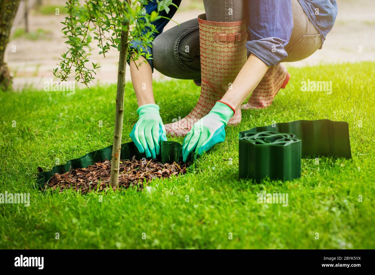 Frau installieren Kunststoff Rasen Kanten um den Baum im Garten Stockfoto