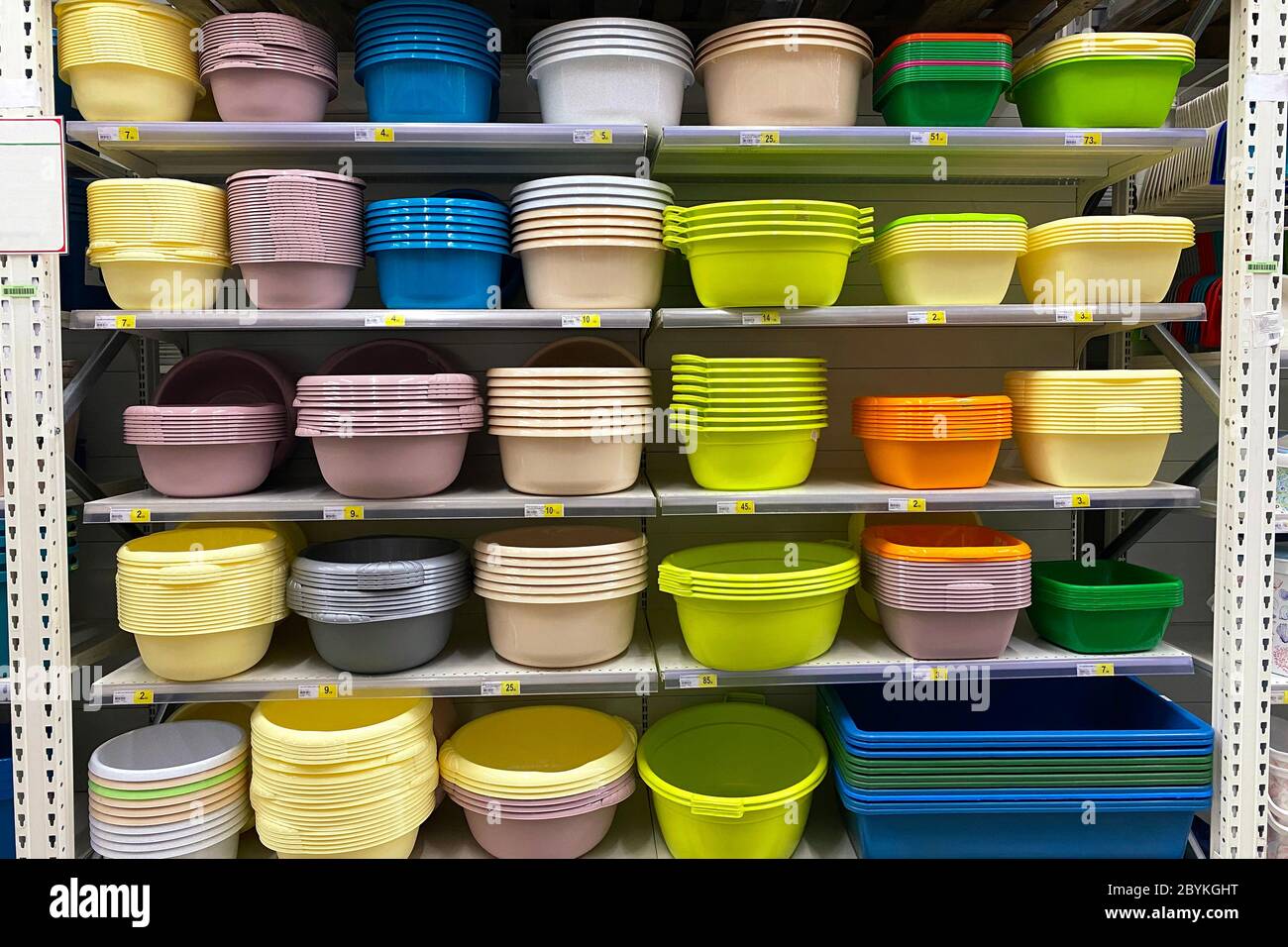 Einkaufen mit Hintergrund von bunten Plastikkörben, Schalen und Waschbecken im Regal. Preiswerte Alternative zu Gerichten aus natürlichen Materialien. Stockfoto