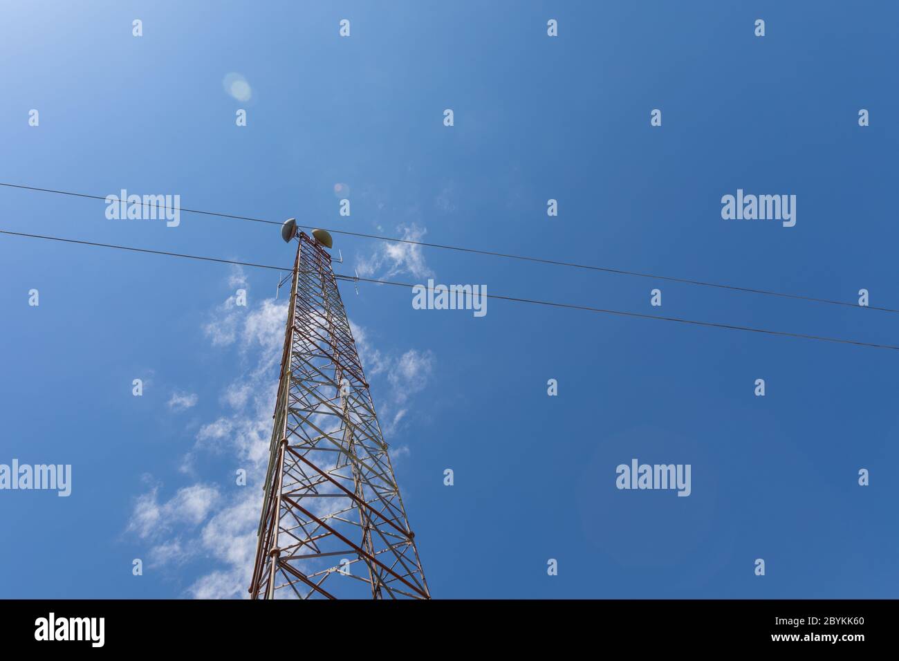 Extrem hoher Telekommunikationsturm von unten mit Mikrowellenantennen, Silhouetten vor einem schönen blauen Himmel mit spärlichen Wolken, Kopie Spa Stockfoto